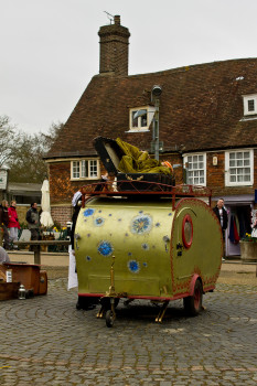 A performer folds herself into a suitcase, on top of a tiny caravan, outside Battle Abbey